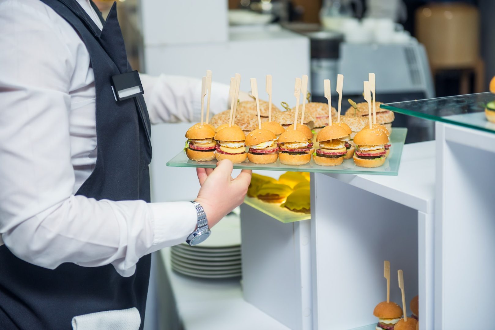 The waiter is serving a catering buffet table with food and snacks for guests of the event.